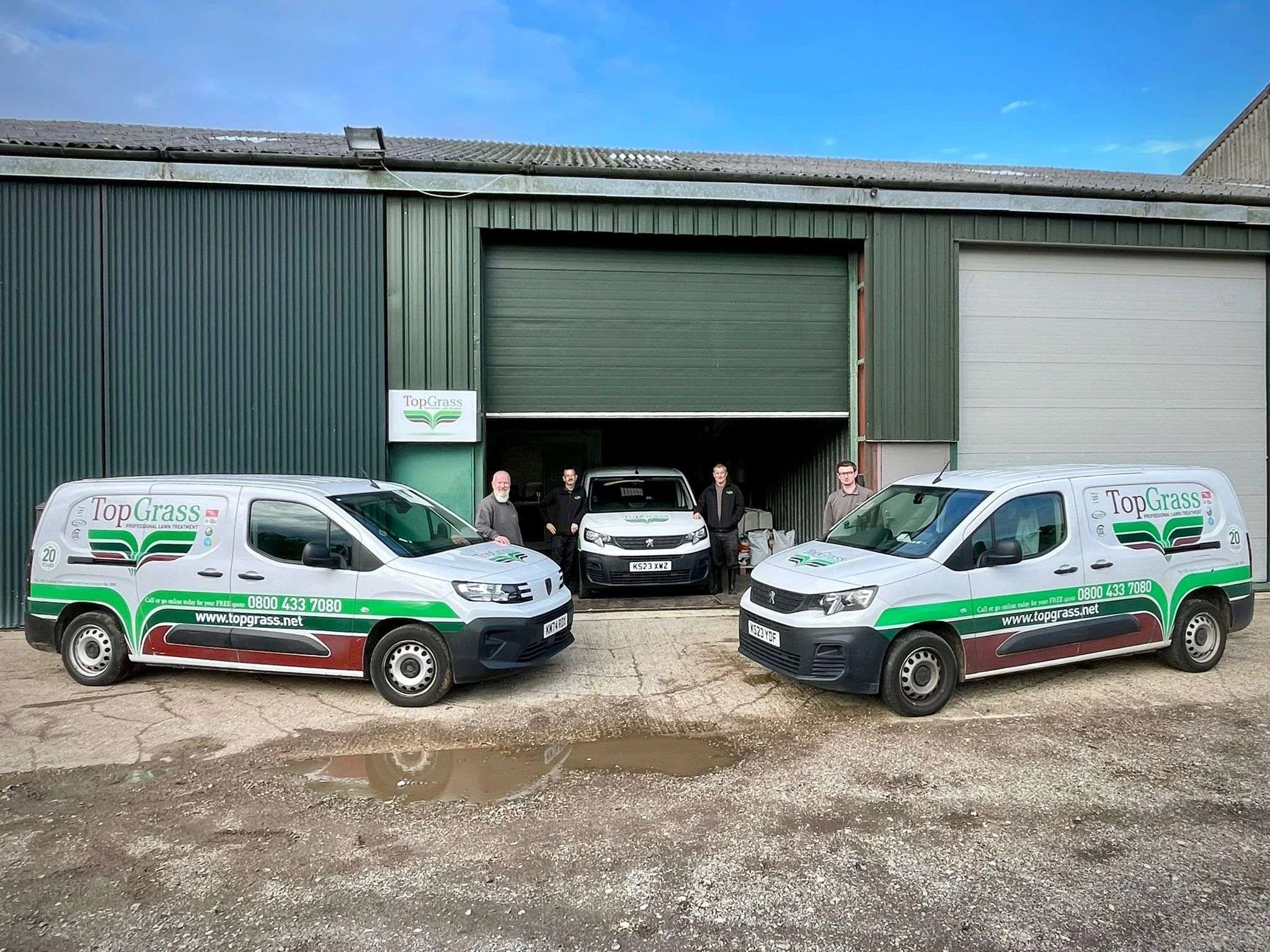 Image of a lawncare depot with topgrass branded vans parked outside, with workers in the picture as well